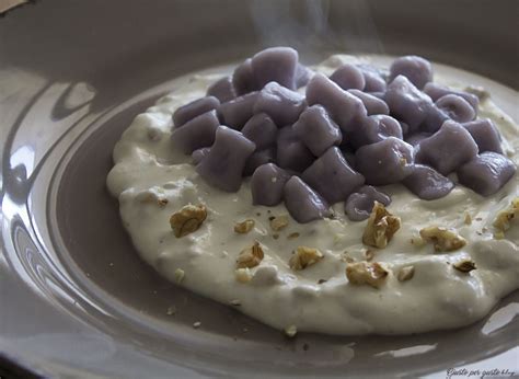 Piatto finito di gnocchi di patate viola con fonduta e mele caramellate