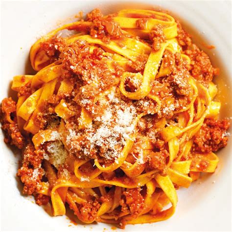 Piatto di fettuccine alla bolognese fumanti, condite con ragù e parmigiano