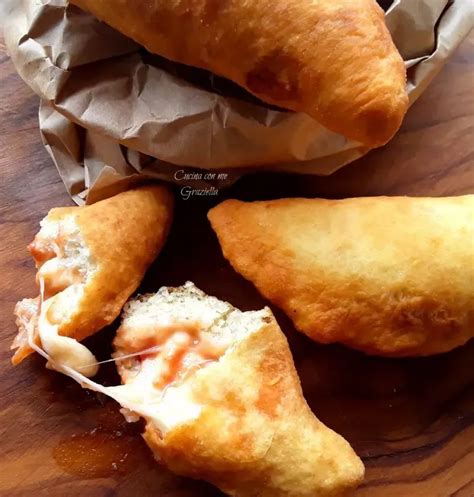 vassoio di panzerottini pugliesi dorati, alcuni fritti e altri al forno, con una spolverata di zucchero su quelli al forno