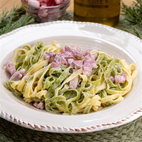 Immagine di un piatto finito di tagliatelle paglia e fieno alla boscaiola, guarnito con prezzemolo fresco.