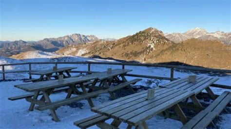 Esterno del Rifugio Gherardi, situato in un'area boschiva, con tavoli all'aperto.