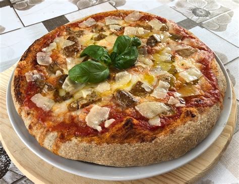Infografica comparativa: pizza con farina integrale vs. pizza con farina bianca, con focus sull'impatto glicemico.