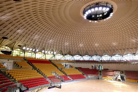 vista esterna di un moderno palazzetto dello sport con campi sportivi circostanti