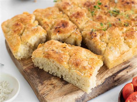 Immagine di una teglia di focaccia bianca con buchi evidenti, pronta per essere condita