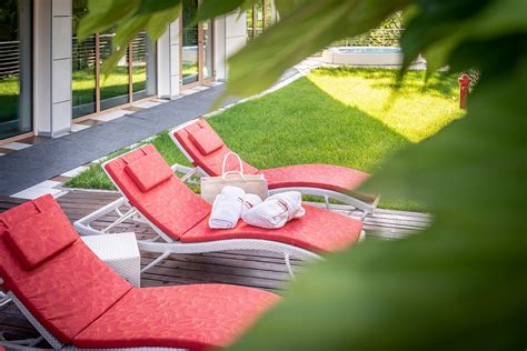 Area relax esterna di un B&B con piscina, tavolini, sedie e vegetazione circostante.
