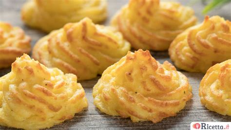 Patate duchessa decorate con sac à poche disposte su una teglia