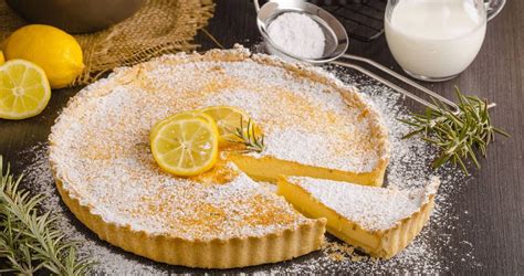 Immagine di una torta al limone e zabaione finita, con decorazioni di panna montata e scorza di limone.