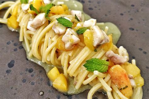 Immagine di un piatto di pasta con cernia e melanzane, guarnito con foglie di menta fresca