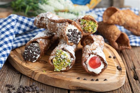 Una selezione di cannoli siciliani con diverse decorazioni, disposti su un vassoio.