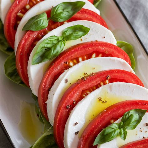 Gros plan sur des ingrédients frais : tomates juteuses, boule de mozzarella di bufala et un bouquet de basilic frais.