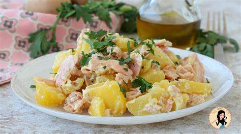 Una ciotola colorata con insalata di patate e salmone affumicato, guarnita con prezzemolo fresco tritato.