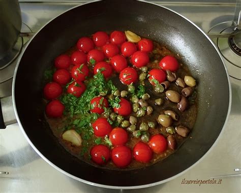 Primo piano di pomodorini, olive e capperi che vengono aggiunti al sugo di cottura del polpo.