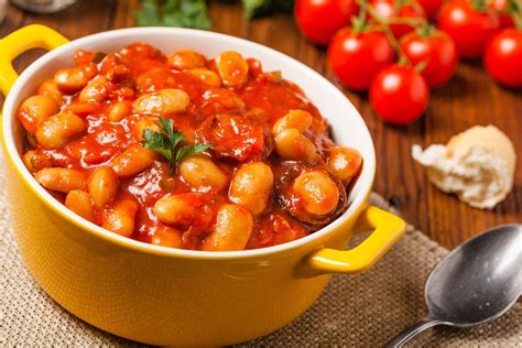 Una padella fumante di fagioli con salsiccia e pancetta, in stile rustico