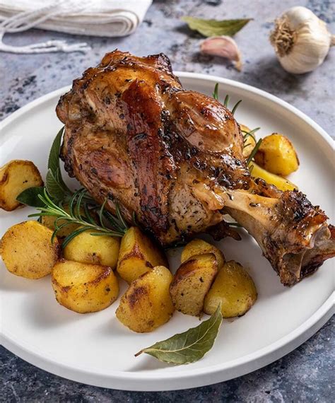 Piatto presentato con lo stinco al forno e una ciotola separata con lo stufato di fagioli.