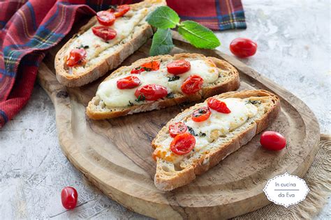 Primo piano di una bruschetta condita con pomodorini freschi, alici e origano