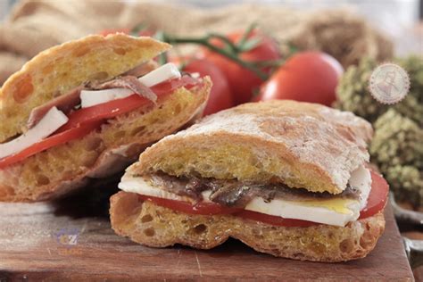 Pane cunzato con primo sale, alici, pomodorini e origano, pronto per essere servito
